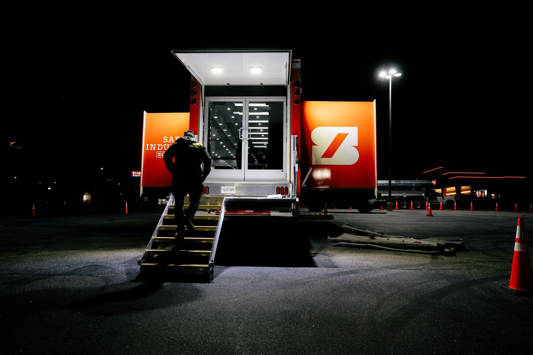 A Safe Industries mobile command unit deployed at night. One team member climbs the steps into the lit doorway.